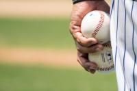 Baseball player on the mound holding two baseballs.